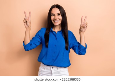 Photo of gorgeous lovely glad girl wear blue stylish clothes two arm demonstrate v-sign symbol isolated on beige color background