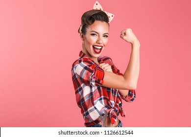 Photo of gorgeous strong young pin-up woman isolated over pink background wall showing biceps.