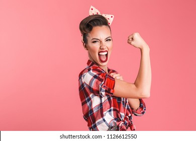 Photo of gorgeous strong young pin-up woman isolated over pink background wall showing biceps screaming.