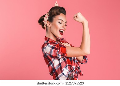 Photo of gorgeous strong young pin-up woman isolated over pink background wall showing biceps.