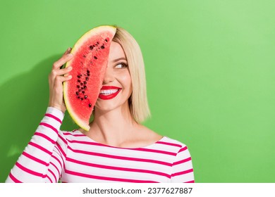 Photo of gorgeous woman with bob hairstyle wear striped shirt hold watermelon on eye look empty space isolated on green color background