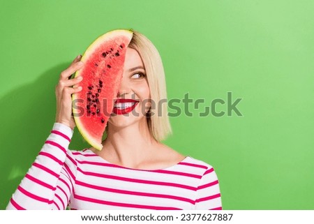 Photo of gorgeous woman with bob hairstyle wear striped shirt hold watermelon on eye look empty space isolated on green color background