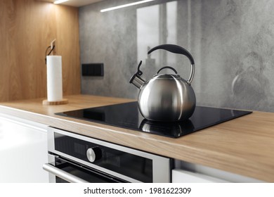 Photo of gray stainless steel kettle on the induction cooktop in the kitchen. - Powered by Shutterstock