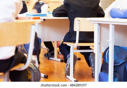 Photo Of  Group Of School Kids Sitting And Listening To Teacher In Classroom From Back