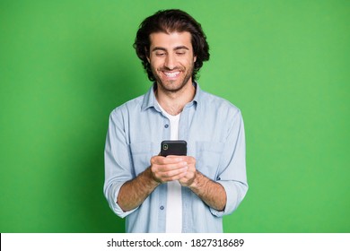 Photo of guy hold telephone look screen white shiny smile wear denim shirt isolated green color background - Powered by Shutterstock