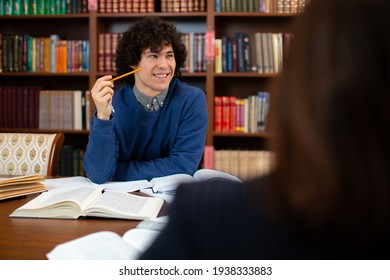 Photo Of A Guy Scientist Who Sits In The Library, Working On A Project And Smiling. Student Science. High Quality Photo