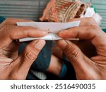 Photo of a hand rolling tobacco traditionally. A man