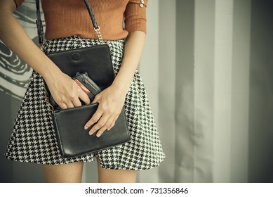 Photo of hand of young woman pulling a pistol out of her handbag with free copy space. Self defences concept