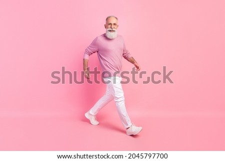 Photo of handsome attractive mature man dressed pullover glasses smiling walking isolated pink color background
