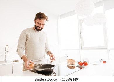 Photo Of Handsome Bachelor With Short Brown Hair And Beard Cooking Omelet With Vegetables In Home Kitchen Using Frying Pan