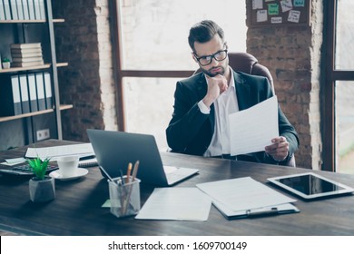 Photo of handsome business brunet guy reading paper report noticed wrong income stats numbers looking for mistakes wear black blazer shirt suit sitting chair office indoors - Shutterstock ID 1609700149