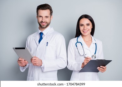 Photo Of Handsome Busy Family Doc Guy Lady Virology Clinic Listen Client Experienced Doctors Write Paper Online Prescription Tablet Clipboard Wear Lab Coats Isolated Grey Color Background