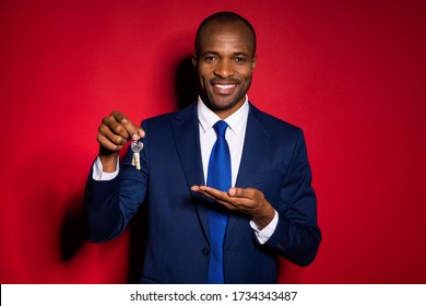 Photo of handsome dark skin business guy confident worker hold open arm offer sale price demonstrating keys chain wear formalwear suit tuxedo isolated burgundy red background