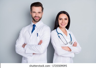 Photo of handsome doc guy lady patient consultation virology clinic stand back-to-back toothy smiling arms crossed experienced doctors wear lab coats isolated grey color background