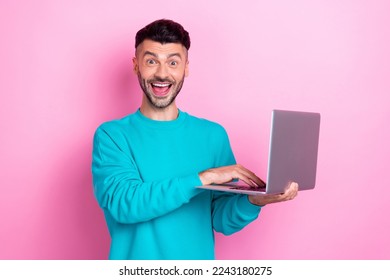 Photo of handsome funny face guy hold his laptop shock eshopping proposition cheap clothes from amazon isolated on pink color background