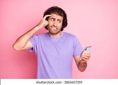 Photo Of Handsome Man Scared Loon Phone Hand On Forehead Bite Lip Violet Outfit Isolated On Pastel Pink Color Background