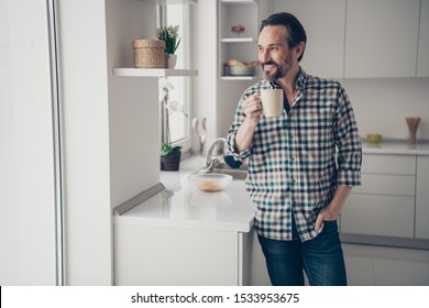 Photo of handsome positive optimistic nice glad attractive guy holding cup of fresh cacao in hands looking in window at falling leaves standing in kitchen - Powered by Shutterstock