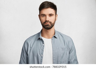 Photo Of Handsome Serious Bearded Man With Thick Black Mustache And Beard Wears Shirt, Looks Confidently Into Camera, Has Serious Expression As Listens Important Information Isolated On White