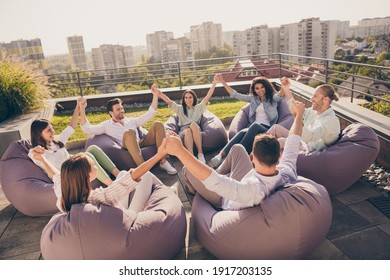 Photo Of Happy Agents Sitting Beanbags Corporate Trust Training Rising Arms Workplace Workstation Outdoors Outside Urban Terrace