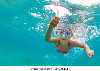Photo of happy baby girl jump, dive underwater with fun in tropical lagoon pool. Travel lifestyle, water sport, snorkeling adventure. Family swimming lessons on summer sea beach vacation with kids
