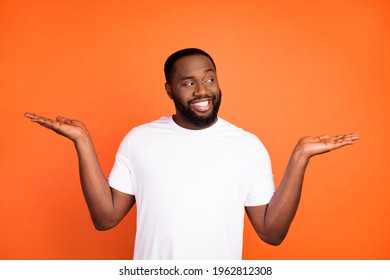 Photo of happy brunette afro american dream young man look hands empty space isolated on orange color background