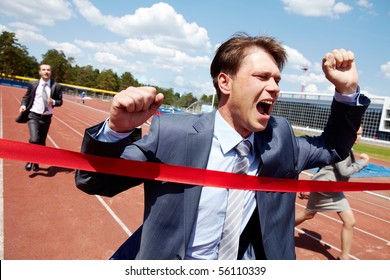 Photo Of Happy Businessman Crossing Finish Line During Race