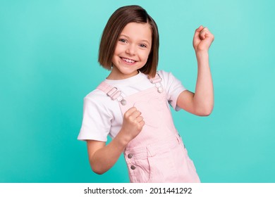 Photo Of Happy Charming Nice Little Girl Winner Raise Fists Smile Isolated On Pastel Teal Color Background