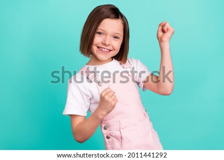 Photo of happy charming nice little girl winner raise fists smile isolated on pastel teal color background