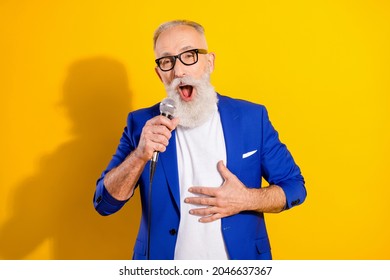 Photo Of Happy Cheerful Old Man Sing Hold Hand Mic Karaoke Wear Glasses Isolated On Yellow Color Background