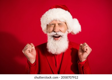 Photo Of Happy Cheerful Old Man Christmas Santa Claus Hat Winner Celebrate Isolated On Red Color Background