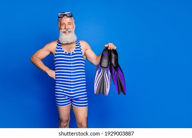 Photo Of Happy Cheerful Positive Handsome Old Man Hold Slippers Prepare To Swim In Pool Isolated On Blue Color Background