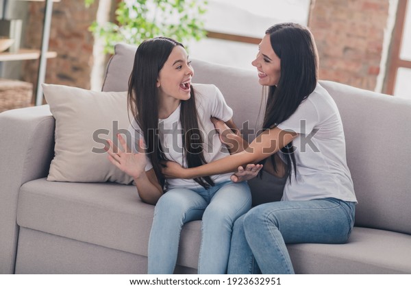 Photo of\
happy cheerful smiling family mother and daughter playing mom\
tickling little girl sit sofa at home\
house