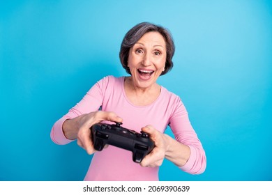 Photo of happy excited cheerful smiling crazy grandmother feeling young playing playstation isolated on blue color background