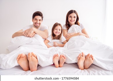 Photo of happy family barefoot legs mommy daddy kid lying sheets sleeping awakening morning spend together quarantine weekend saturday sunday self isolation bedroom indoors