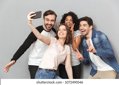 Photo of happy group of friends standing isolated over grey wall background looking aside make a selfie. - Shutterstock ID 1072490546