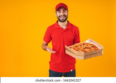 Photo of happy joyful man in red uniform smiling and holding pizza box isolated over yellow background