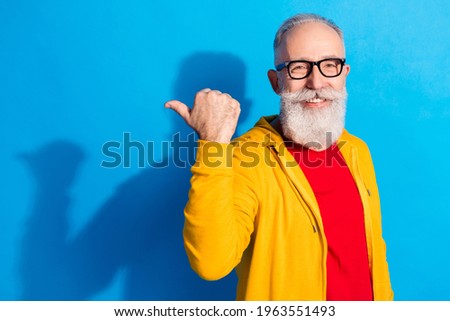 Photo of happy positive handsome cheerful mature man in glasses advertising product isolated on blue color background