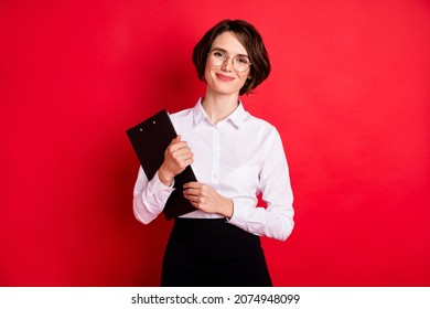 Photo of happy positive lovely charming secretary in glasses hold organizer smiling isolated on red color background
