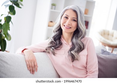 Photo of happy positive nice charming old woman sit couch good morning smile indoors inside house home
