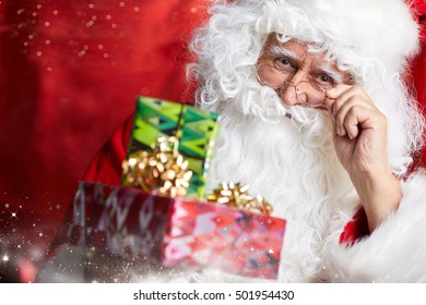 Photo of happy Santa Claus outdoors in snowfall carrying gifts to children - Powered by Shutterstock