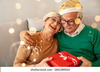 Photo of Happy senior couple exchanging Christmas presents during the day at home. Elderly woman giving present to her beloved husband. Gray hair couple celebrating New Year - Powered by Shutterstock