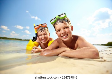 Photo of happy siblings lying on sand on summer vacation