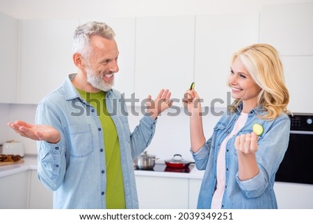 Photo of happy smiling cheerful married couple spouses fooling around wife hold slice of cucumber enjoying weekend
