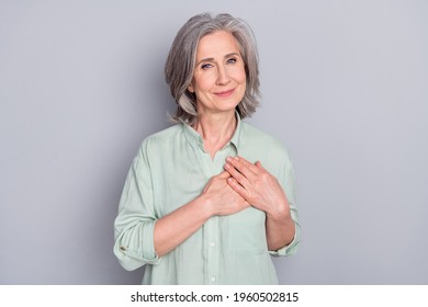 Photo of happy smiling dreamy lovely granny hold hands chest thankful grateful isolated on grey color background