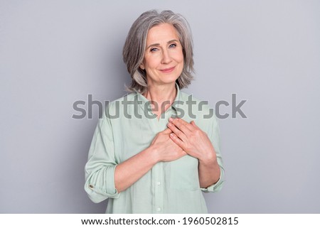 Photo of happy smiling dreamy lovely granny hold hands chest thankful grateful isolated on grey color background