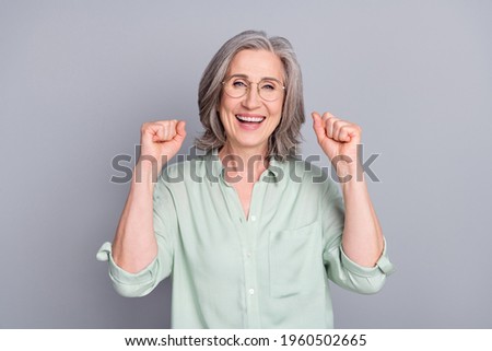 Photo of happy smiling excited funky funny mature woman raise fists in victory success isolated on grey color background
