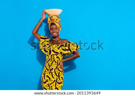 Photo of happy smiling good mood african woman look copyspace hold cly plate on head isolated on blue color background