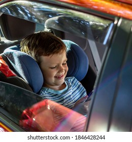 Photo Of A Happy Smiling Young Boy Riding In Car,using Social Network On Smartphone. Photo Of Young Male Passenger Sitting On Car Back Seat Using A Mobile. Toddler Sitting In A Car Playing With Phone.