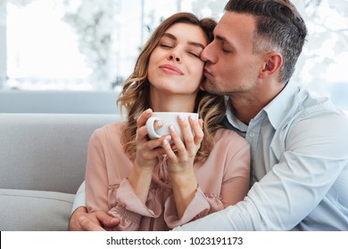 Photo of happy tender man and woman hugging and enjoying stay together in city cafe with cup of hot tea స్టాక్ ఫోటో