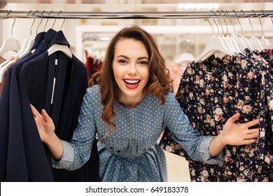 Photo Of Happy Young Lady Standing In Clothes Shop. Looking At Camera.